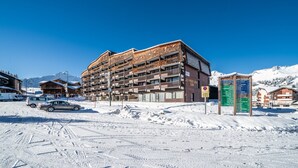 A multi-story hotel with a brick facade, balconies, and a signboard with room information. - Apartment 'Les Mouflons 1500' with Mountain View, Balcony and Wi-Fi (Taninges)