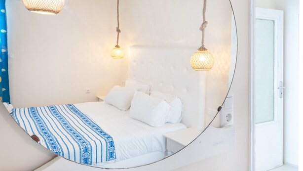 Une chambre à coucher avec un lit, des murs blancs et deux lampes suspendues.