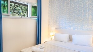 Hotelkamer met een bed, een raam met uitzicht op bomen, een lamp en een muur met een patroon.