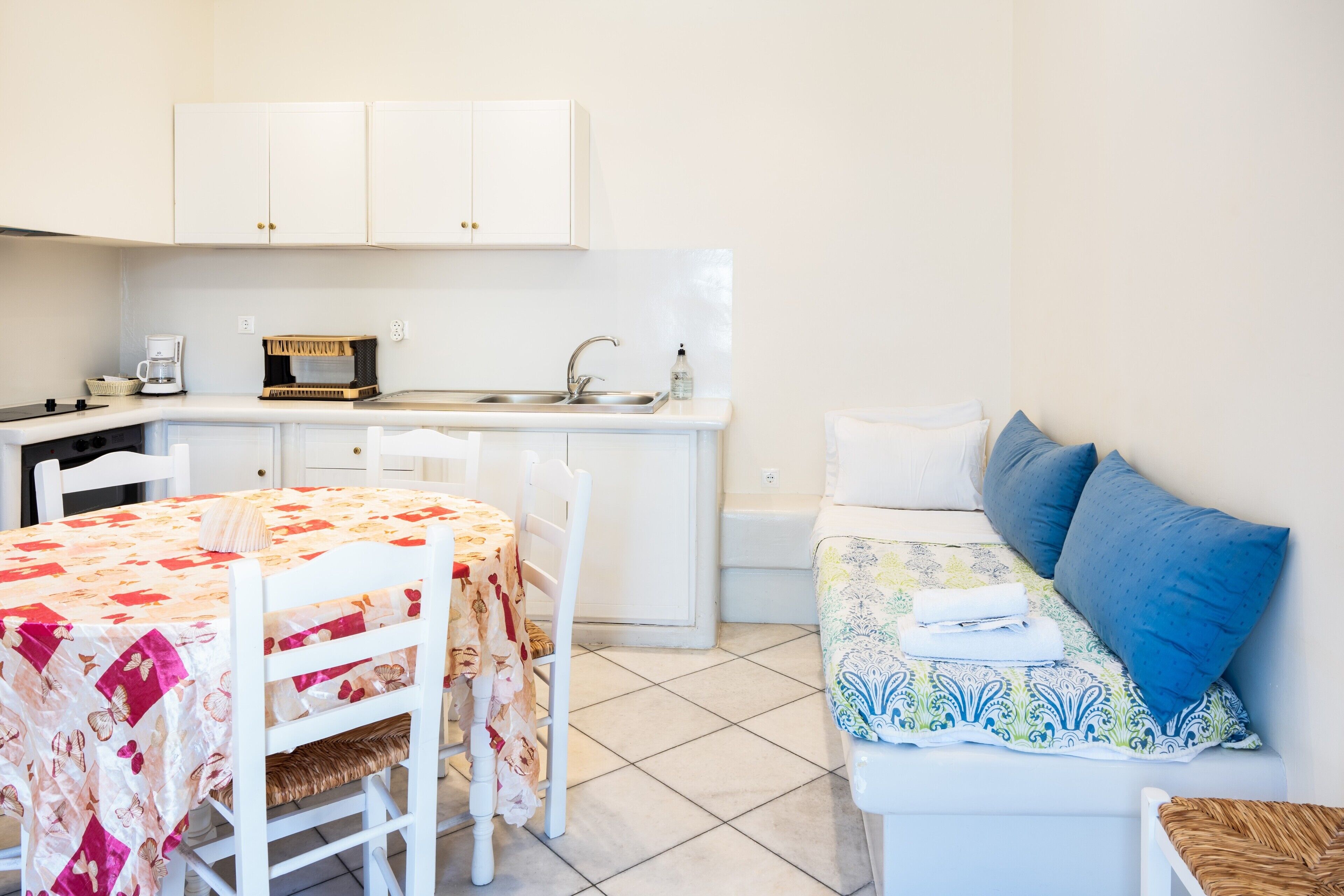A compact kitchen with a dining table, chairs, and a small sink.