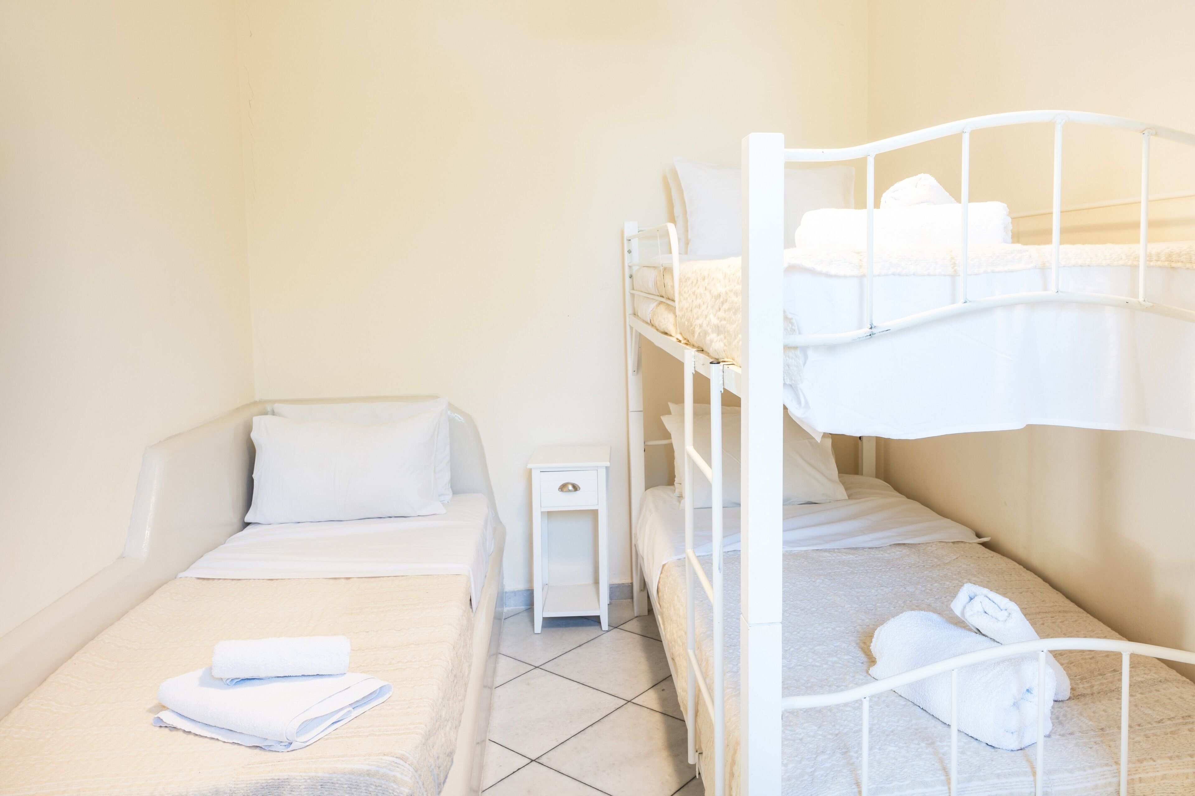 A bunk bed room with a single bed, a nightstand, and neatly folded towels.
