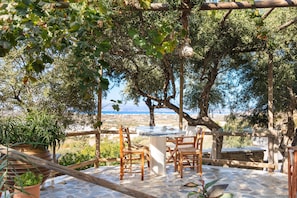 A stone patio with a table and chairs, surrounded by trees and a view of the landscape.