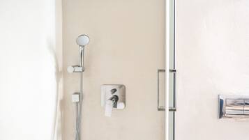 Ducha con cabezal de ducha de mano y panel de control en la pared.