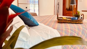 Ein Schlafzimmer mit Bett, Kissen, einem Nachttisch mit Lampe, einem Fenster mit Vorhängen und einer Tür.