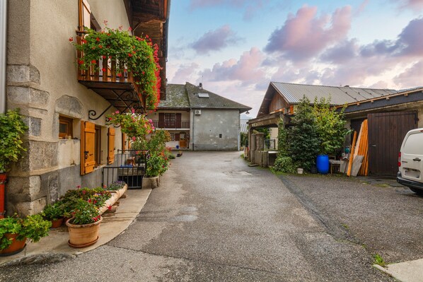 A narrow street with buildings on either side, some with balconies and flower boxes.