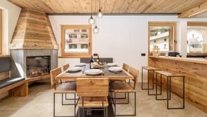 A modern kitchen with a central island, wooden chairs, a built-in stove, and large windows.