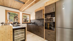 A modern kitchen with wooden cabinetry, a built-in wine cooler, and a stainless steel refrigerator.