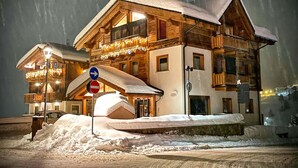 A snow-covered building with a balcony, a stop sign, and a pile of snow in front.