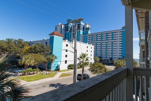 Un hôtel doté d’une façade bleue et blanche très visible, d’un grand parking et offrant une vue dégagée sur les environs, notamment sur les palmiers et la plage.