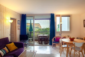 Un salon comprenant un canapé, un téléviseur et un coin repas avec une table et des chaises.