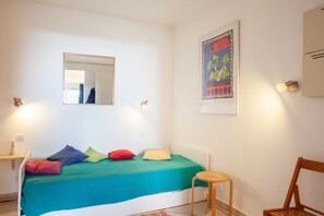 Une chambre à coucher avec un lit, une table de chevet, une chaise et une affiche accrochée au mur.