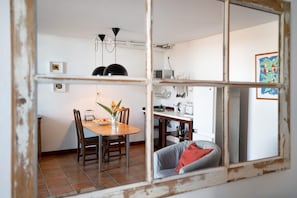 Een eetgedeelte met een houten tafel, stoelen en een vaas met bloemen.