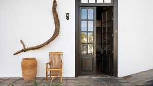 L'ingresso di un edificio con una panca di legno, un grande vaso in terracotta e un'originale decorazione a ramo di legno.