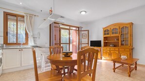 Une cuisine avec un coin repas, des meubles de rangement en bois et un téléviseur.