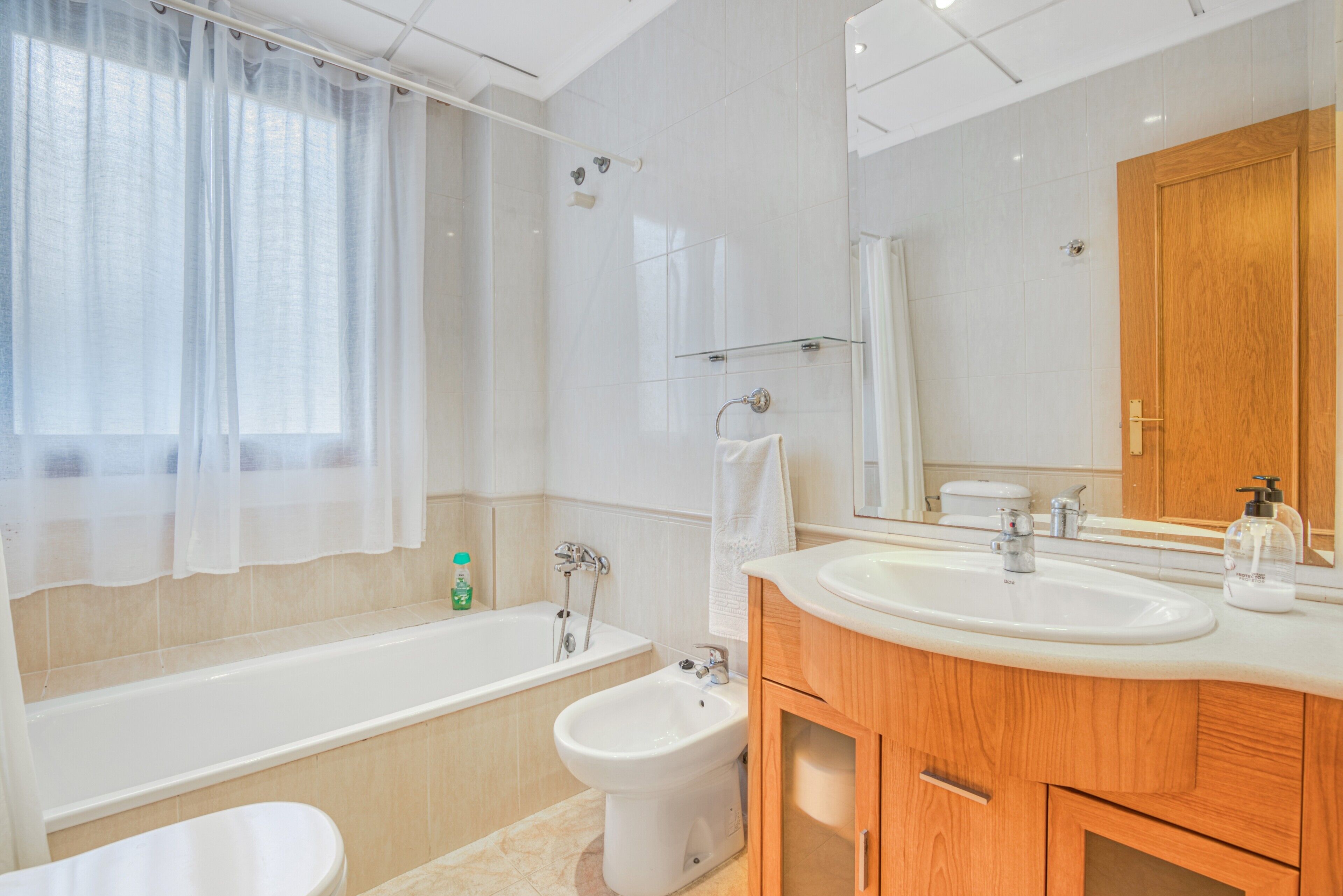 Ein modernes Badezimmer mit einer Badewanne, einer Dusche, einer Toilette und einem Waschtisch mit Spiegel.