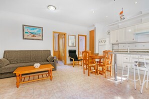 Un salon comprenant un canapé, une table basse en bois et un coin repas avec des chaises et une table.