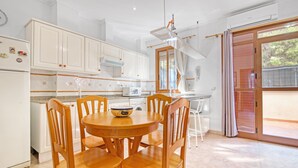 Une cuisine moderne avec des meubles blancs, une table ronde en bois et une grande fenêtre.