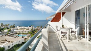 Ein Balkon mit Blick auf das Meer, ein Pool und ein Resortkomplex.