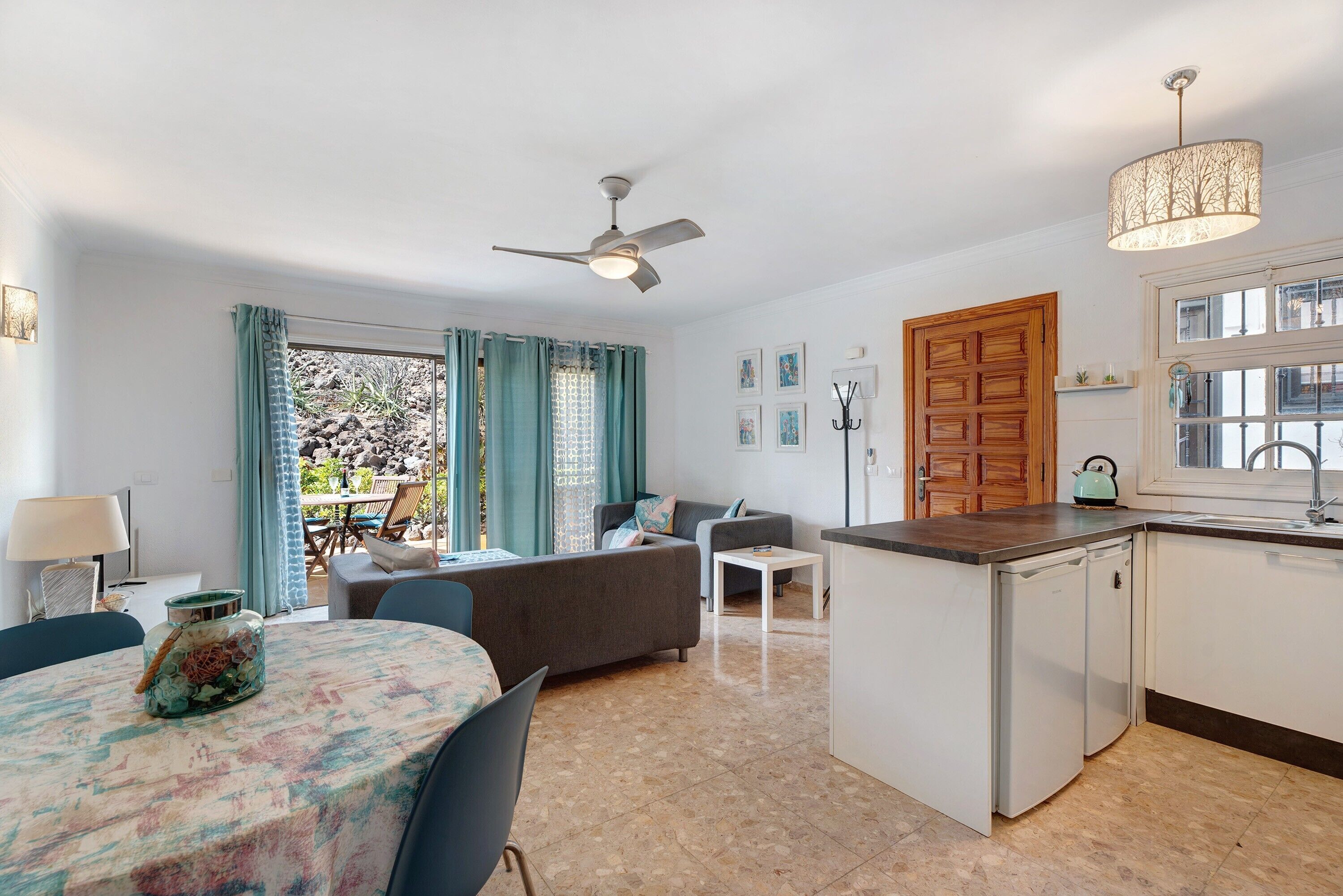 Eine moderne Küche mit Geschirrspüler, ein Essbereich mit Tisch und Stühlen, eine Couch und ein Deckenventilator.
