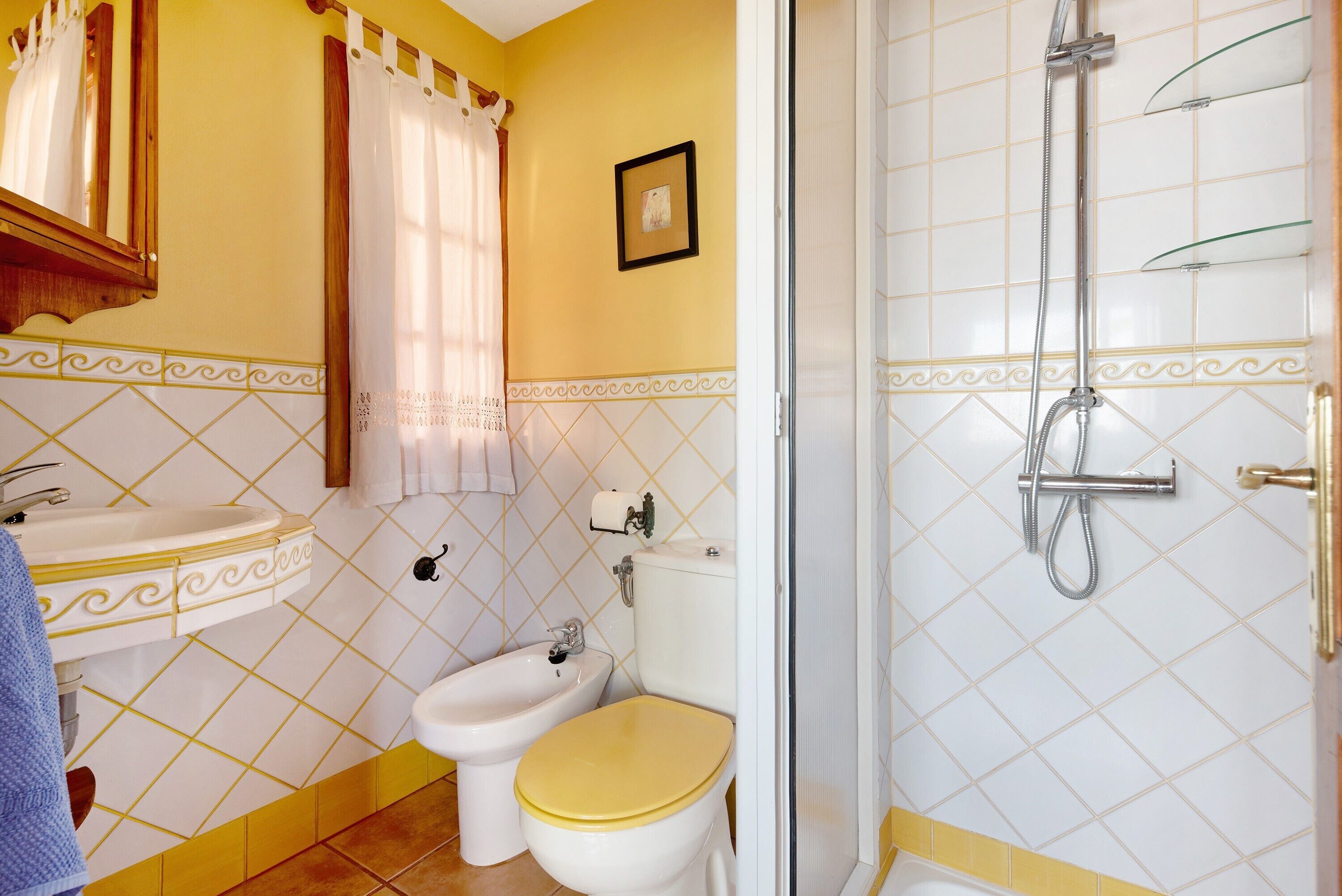 A bathroom with a sink, bidet, toilet, and shower.