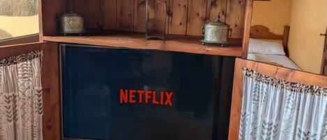 A wooden TV stand with a Netflix logo, a small statue, and a framed picture on top.