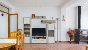 A living room with a TV, wooden cabinets, a dining table, and a fireplace. - Holiday Home "La Matea" with Private Terrace, Balcony and Wi-Fi (LLAURÍ)