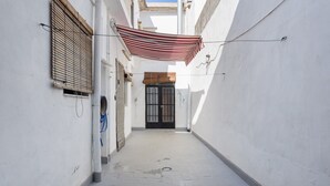 A narrow alleyway with a door at the end, a striped awning, and a window with blinds. - Holiday Home "La Matea" with Private Terrace, Balcony and Wi-Fi (LLAURÍ)