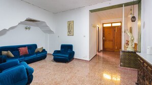 A room with a blue sofa set, a matching armchair, a marble floor, a wooden door, and a statue on a cabinet. - Holiday Home "La Matea" with Private Terrace, Balcony and Wi-Fi (LLAURÍ)