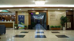 Un'area della reception di un hotel, con una scrivania, una segnaletica per l'amministrazione e il ristorante, e una scala che conduce al piano interrato.