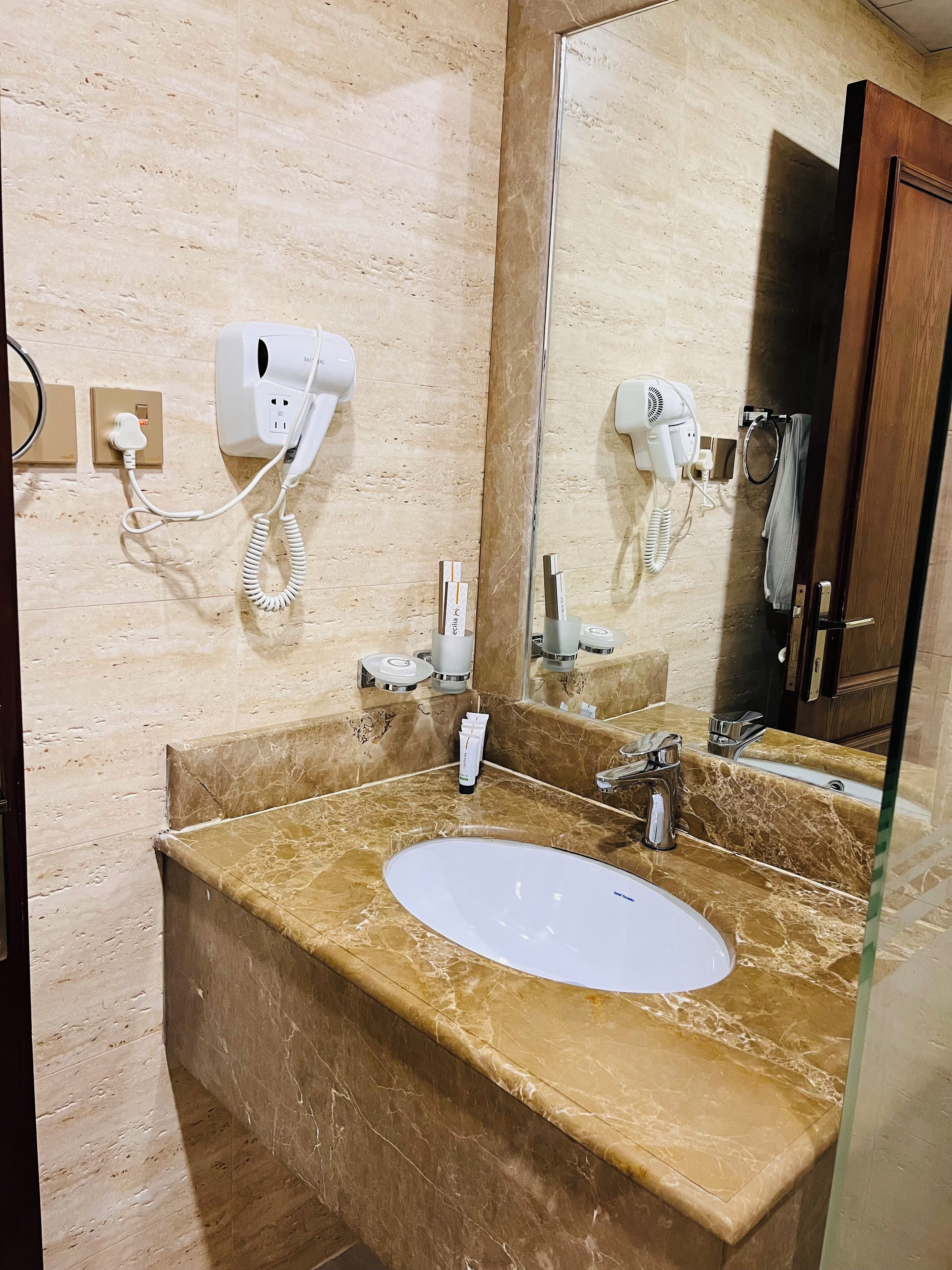 Een badkamer met een marmeren wastafel, een haardroger en een spiegel.