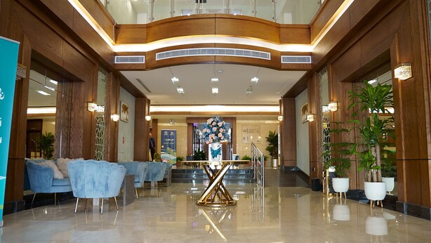 Un'ampia hall con reception centrale, area salotto e piante in vaso.