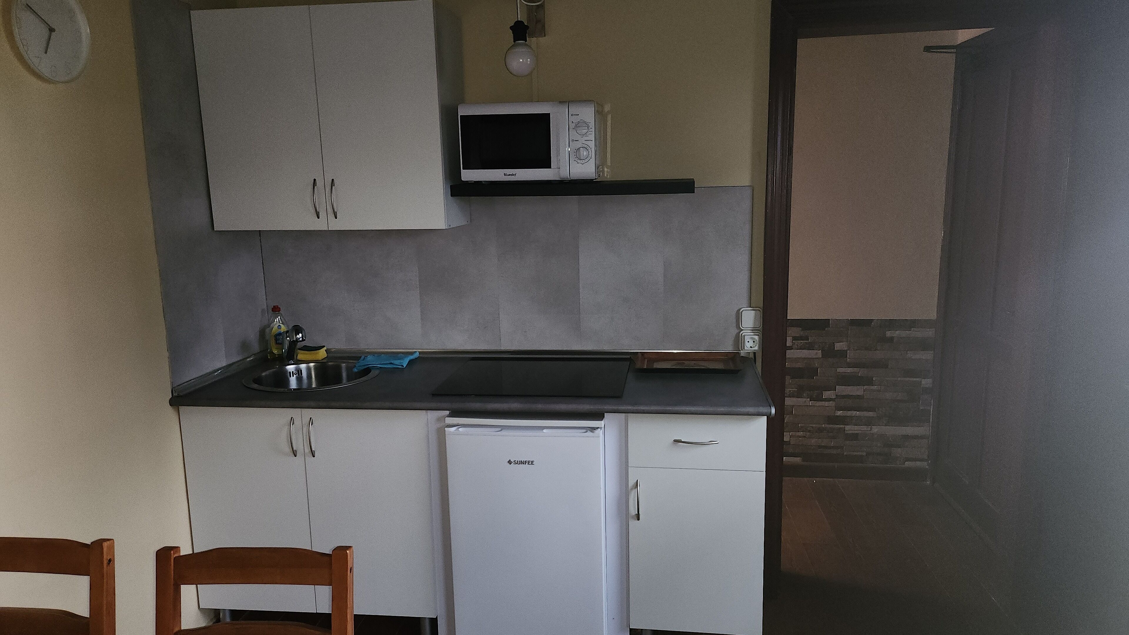 A compact kitchen with a microwave, sink, and a small refrigerator.