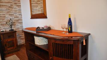Un aparador de madera con una botella, vasos y una tetera.
