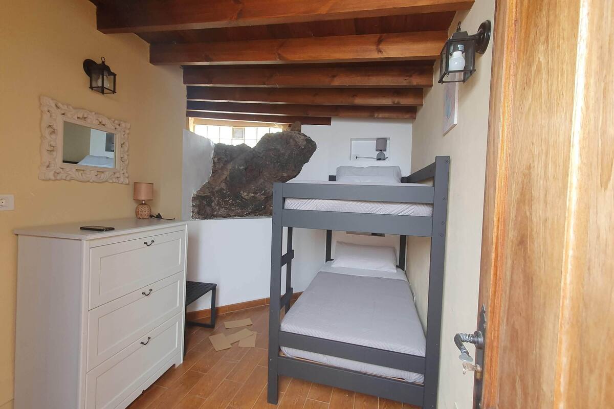 Een slaapkamer met een stapelbed, een dressoir, een spiegel en een lamp.