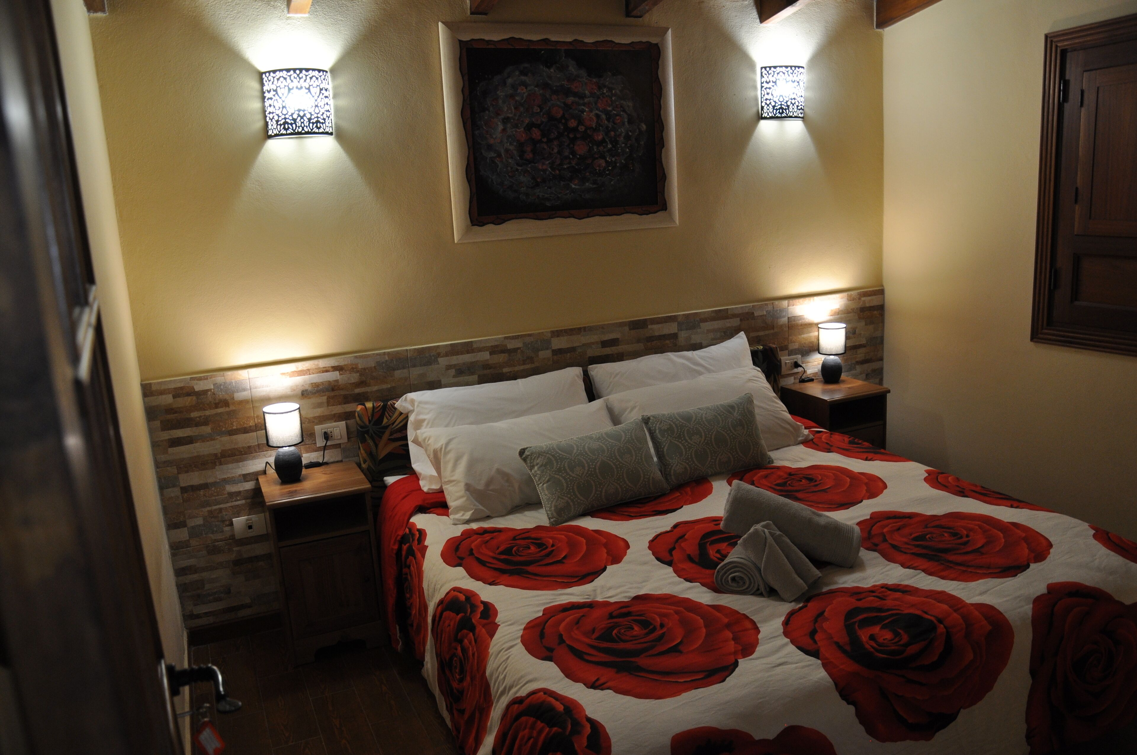 Ein Schlafzimmer mit Bett, Nachttischen, einem Wandbild und zwei Wandleuchten.