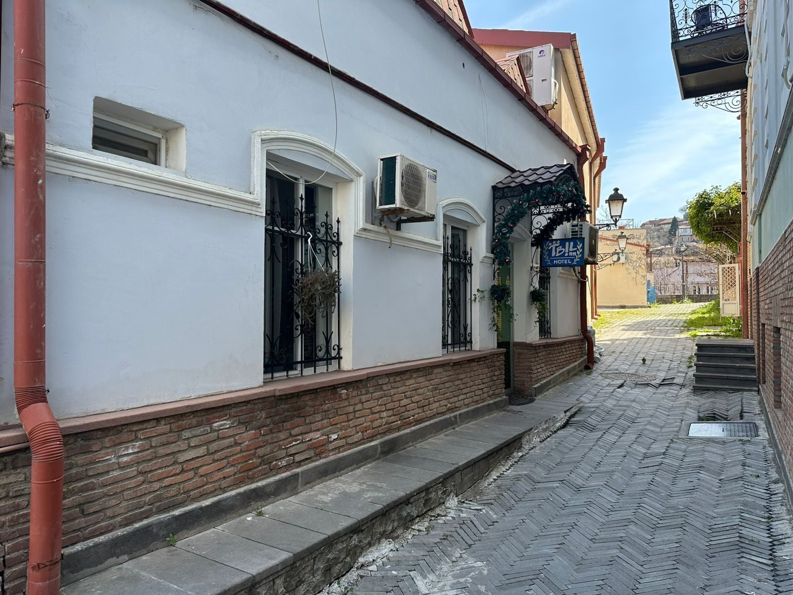 A building with a white facade, a brick base, and a blue sign indicating a hotel.