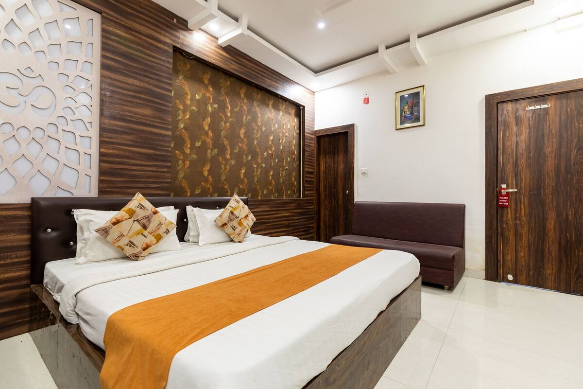 Een moderne hotelkamer met een groot bed, een bank en een houten garderobe.