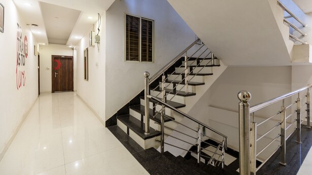 Un interior moderno con una escalera, pisos pulidos y una puerta con un detalle en rojo.