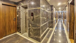 Un ascenseur moderne, avec un revêtement en marbre, une porte en bois et une plaque indiquant le numéro de l’étage : 403.
