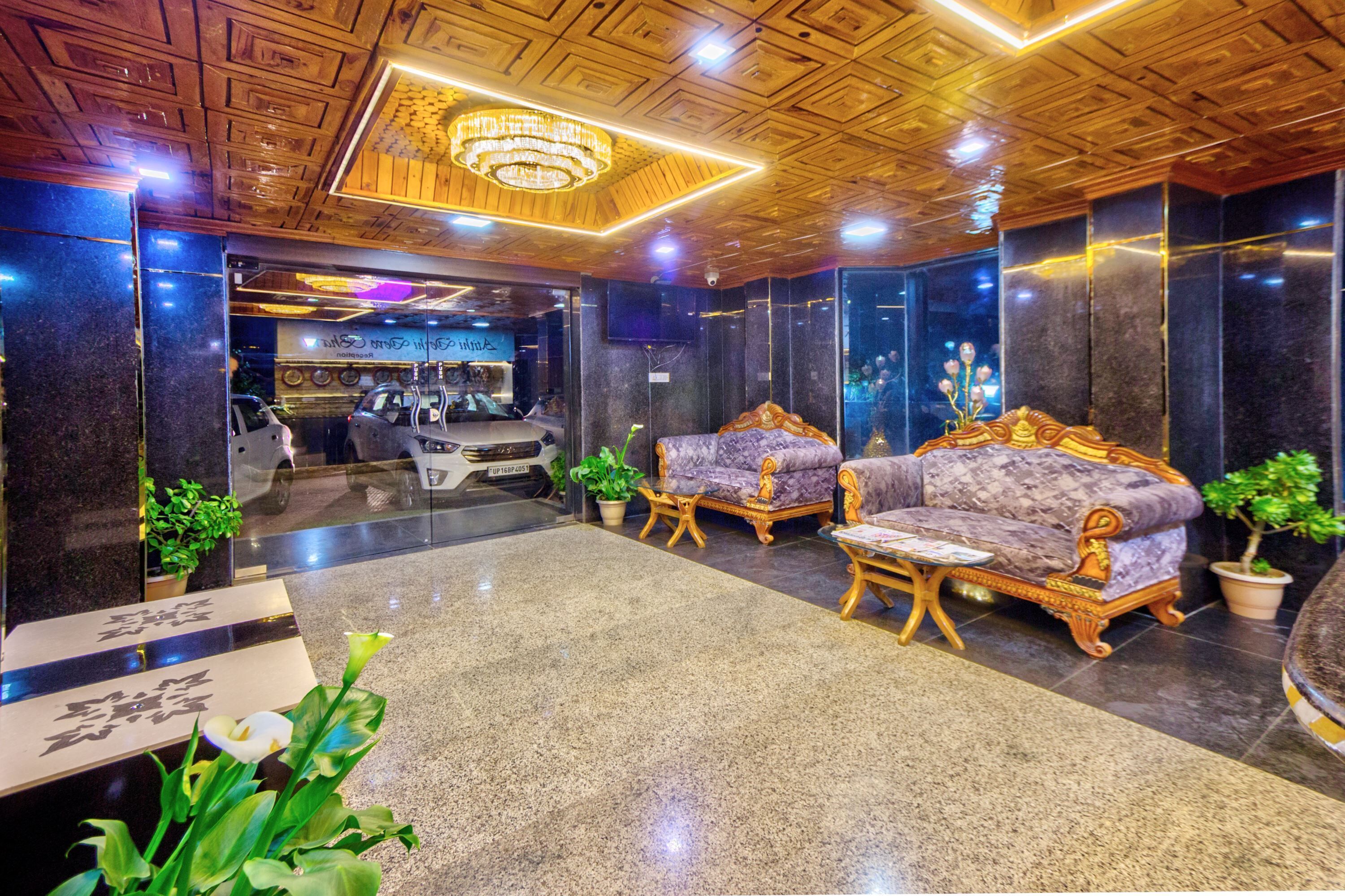 A lobby with a reception desk, a chandelier, and a seating area with a sofa and armchairs.