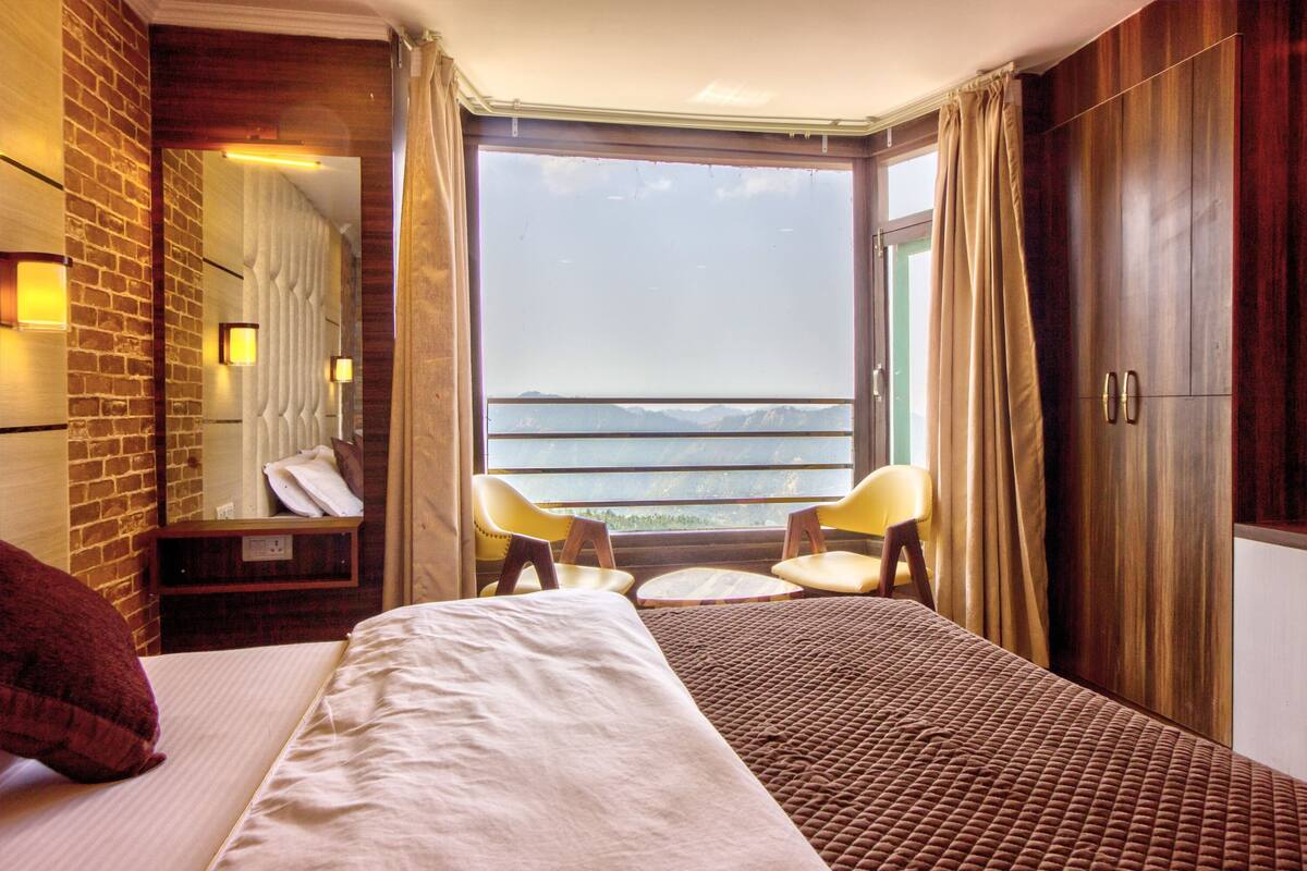 A hotel room with a bed, a chair, a wardrobe, and a view of the sea.