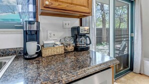 A kitchen with a coffee maker, a basket, and a coffee cup on the counter.
