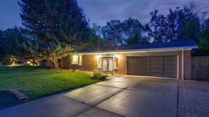 A residential house with a garage, a well-maintained lawn, and a large tree in front.