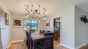 A dining area with a wooden table and chairs, a chandelier, and framed artwork on the walls.
