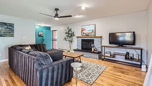 A modern living room with a sectional sofa, a fireplace, a television, and a ceiling fan.