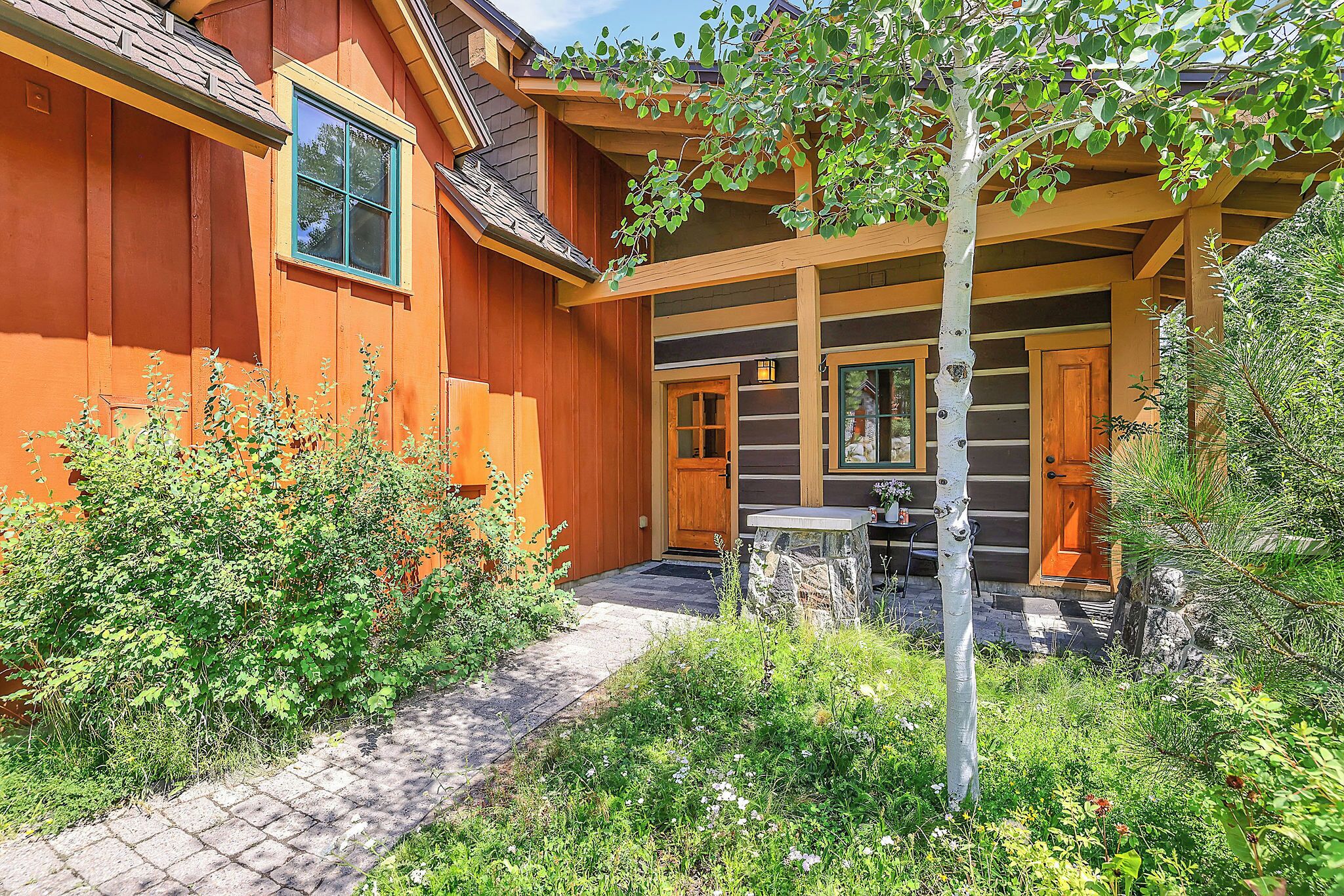 Una casa in legno con un portico coperto, un vialetto in pietra e un piccolo tavolo.