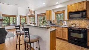 Una cocina moderna con armarios de madera, una isla grande con taburetes de bar, un microondas integrado y un horno.
