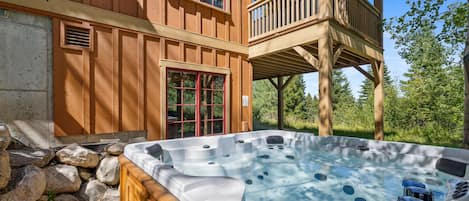 A wooden hot tub with a wooden deck and a balcony.