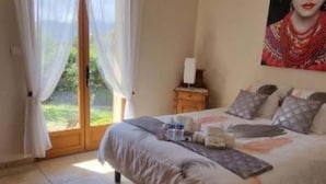 A bedroom with a bed, a nightstand, a painting, and a window with curtains. - Villa 10 Personnes au Calme Entre mer et Montagne. 5 Chambres, 5 Salles de Bain (Vico)