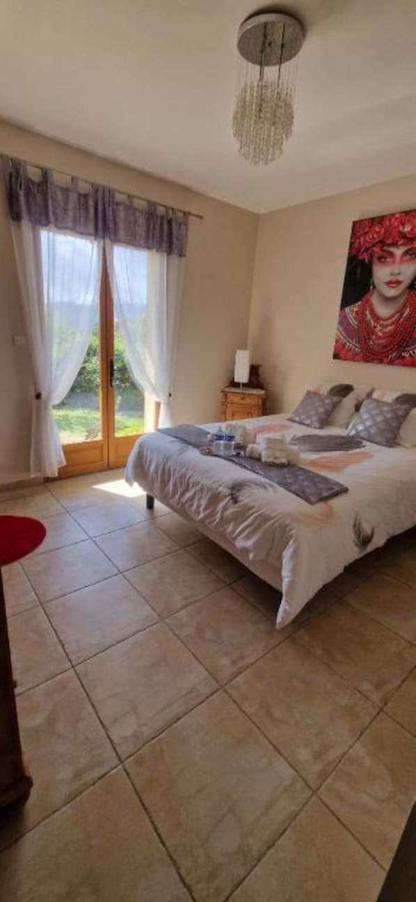 Ein Schlafzimmer mit einem Bett, einem Nachttisch, einem Gemälde und einem Fenster mit Vorhängen.